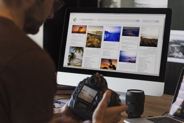 Image of photographer looking at a camera in front of an imac computer